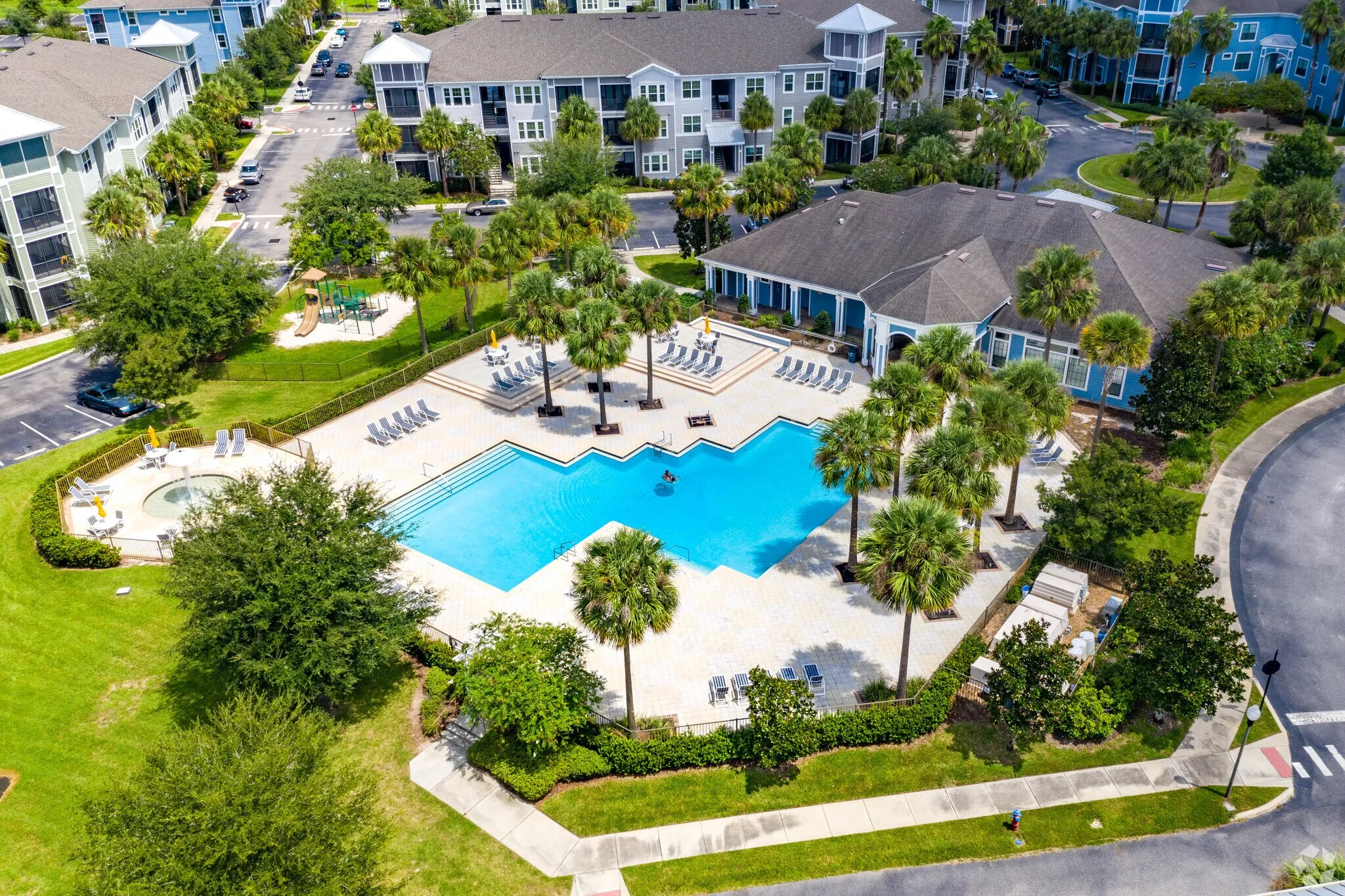 An aerial view of a pool surrounded by palm trees and a resort