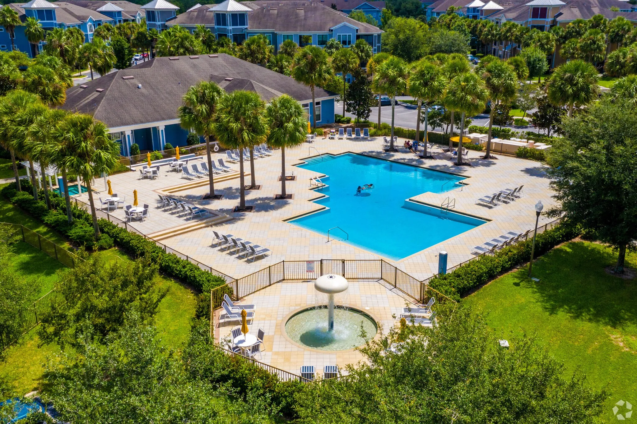A large swimming pool surrounded by trees and a fountain